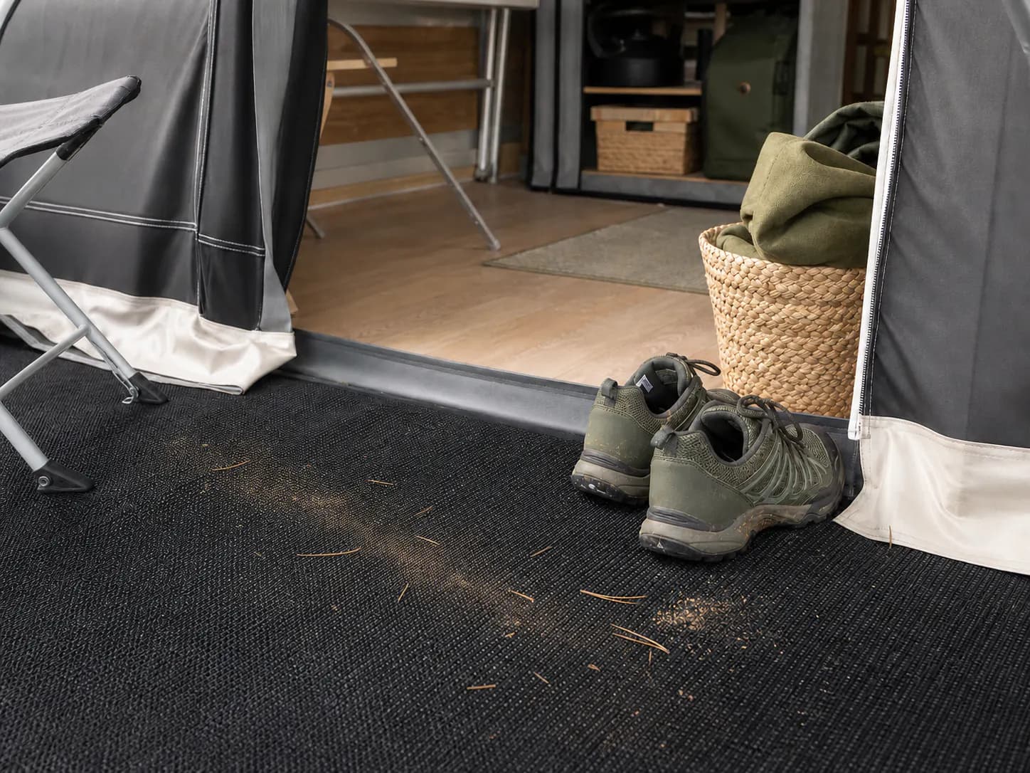 Torr sand och små barr vid ingången till ett förtält på campingen